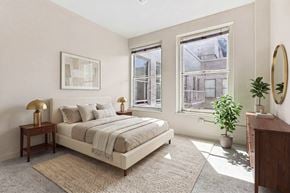 Los Angeles apartment for rent - A bedroom with a large bed, a nightstand with a lamp, a potted plant, and a framed picture on the wall.