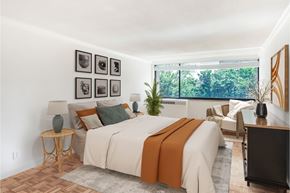 Boston apartment for rent - A bedroom with a large bed and a window overlooking trees.