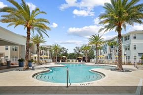 Kissimmee apartment for rent - Resort style swimming pool with palm trees in front of apartment buildings
