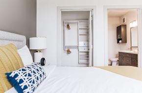 Kissimmee apartment for rent - A white bedroom with a bed, nightstand, and a small bathroom with a toilet and sink.