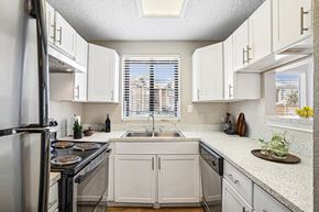 Garland apartment for rent - A kitchen with white cabinets and a black stove top.