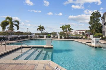 Miramar apartment for rent - A large swimming pool with a diving board and palm trees in the background.