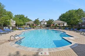 Charlotte apartment for rent - A swimming pool surrounded by a brick patio and lounge chairs.