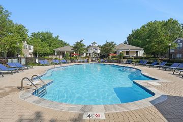 Charlotte apartment for rent - A swimming pool surrounded by a brick patio and lounge chairs.