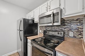 Raleigh apartment for rent - A black refrigerator and microwave are mounted above a stove in a kitchen.