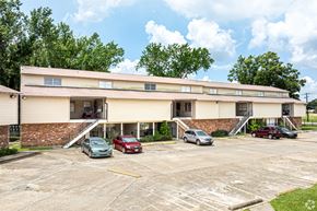 Baton Rouge apartment for rent - A parking lot with a building in the background and several cars parked.