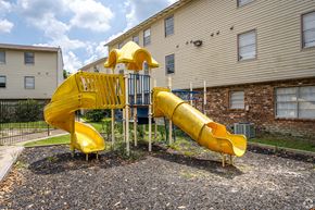 Baton Rouge apartment for rent - A yellow slide in a playground with a building in the background.