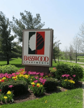 Bloomington apartment for rent - A Basswood Apartments sign is in front of a green lawn.