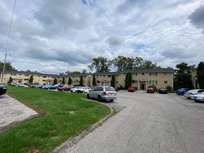 Bloomington apartment for rent - a parking lot filled with cars in front of an apartment building