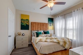 Houston apartment for rent - A bedroom with a bed, nightstand, and a ceiling fan.