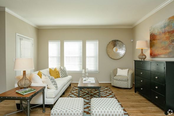 Houston apartment for rent - A living room with a white couch, a coffee table, and a large painting on the wall.