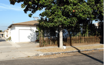 Inglewood apartment for rent - A white house with a brown fence and a tree in front.