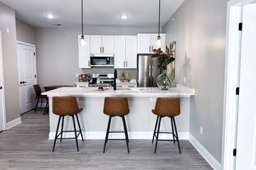 Getzville apartment for rent - A kitchen with a white island and brown barstools.