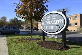 Williamsville apartment for rent - A sign for Village Green Court stands in front of a tree and a building.