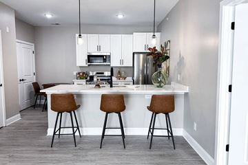 Getzville apartment for rent - A kitchen with a white island and brown barstools.