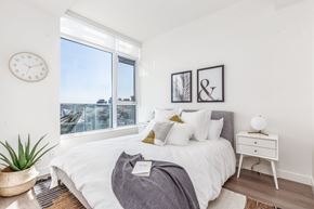 Calgary apartment for rent - A bedroom with a large bed, a nightstand, and a clock on the wall.