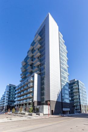 Calgary apartment for rent - A tall, modern building with a white facade stands in the foreground.