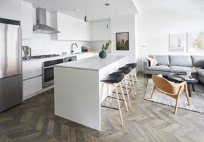 Calgary apartment for rent - A modern kitchen with a white island and wooden flooring.