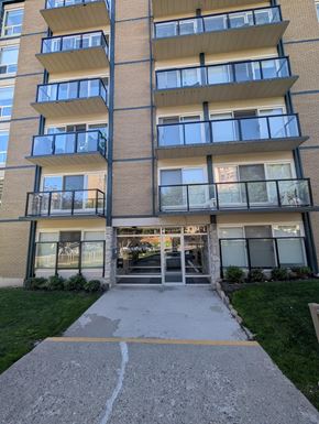 Calgary apartment for rent - A multi-story apartment building with a front entrance and a walkway leading to it.