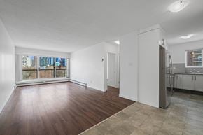 Calgary apartment for rent - A large empty room with wooden floors and a kitchen area to the right.
