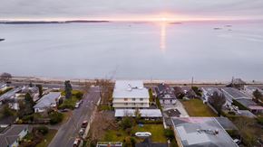 Nanaimo apartment for rent - A sunset view of a residential area with houses and a body of water.