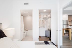 North Vancouver apartment for rent - A white bedroom with a bed, a desk, and a wardrobe.