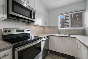 Calgary apartment for rent - A modern kitchen with a stove top oven and microwave above it.