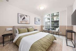Coquitlam apartment for rent - A bedroom with a large bed and a view of a building outside the window.