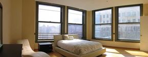 Los Angeles apartment for rent - A bedroom with a bed, chair, and large windows.