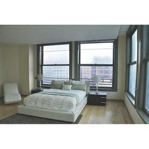 Los Angeles apartment for rent - A bedroom with a large bed and a view of a cityscape through the windows.