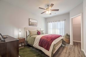 Louisville apartment for rent - A bedroom with a bed, nightstand, and a ceiling fan.