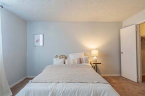 New Albany apartment for rent - A bedroom with a bed, pillows, a nightstand, and a lamp.