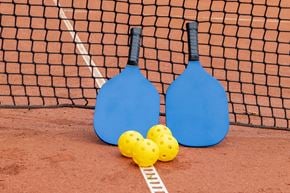 Louisville apartment for rent - Two blue paddles and three yellow balls on a red surface.