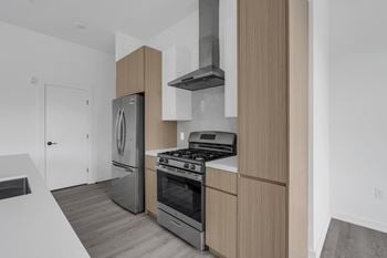 A modern kitchen with a stainless steel refrigerator, oven, and range hood.