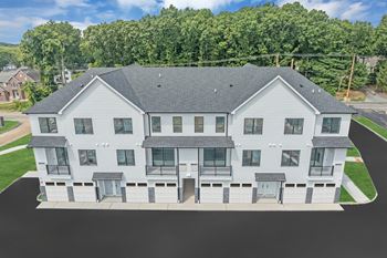 An aerial view of an apartment building with white siding and gray roof
