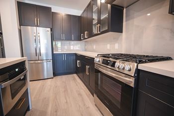 A modern kitchen with black cabinets and stainless steel appliances.