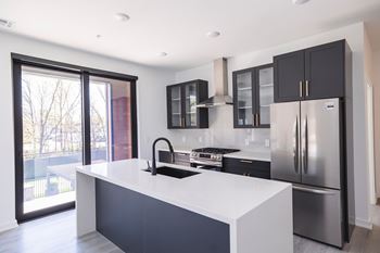 A modern kitchen with a white countertop and stainless steel appliances.