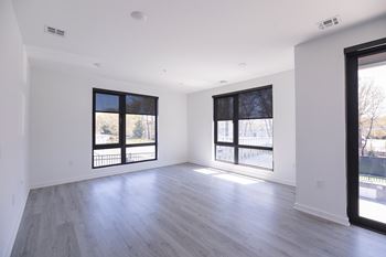 A spacious room with large windows and wooden flooring.