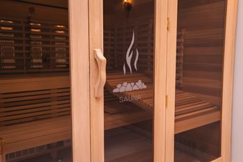 A wooden sauna with a glass door and a handle.