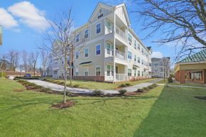 Hillsborough Township apartment for rent - a large apartment building with a lawn and sidewalk in front of it at The Franklin at Hillsborough Apartments, Hillsborough, NJ 08844