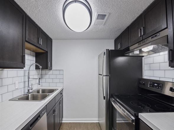 Pensacola apartment for rent - A kitchen with black cabinets and a stainless steel refrigerator at The Palmiere Apartments, Florida