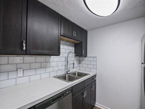 Pensacola apartment for rent - A kitchen with black cabinets and a white countertop at The Palmiere Apartments, Pensacola, 32526