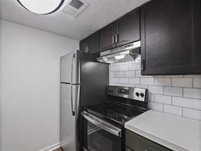 Pensacola apartment for rent - A kitchen with black cabinets and a stove top oven at The Palmiere Apartments, Pensacola, FL, 32526