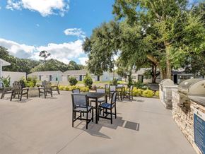 Pensacola apartment for rent - an outdoor patio with tables and chairs and trees at The Papillon, Pensacola Florida