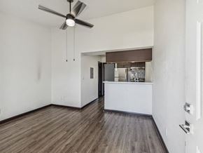 Pensacola apartment for rent - an empty living room with a kitchen and a ceiling fan at The Papillon, Pensacola, 32504