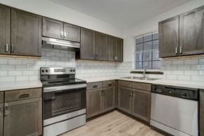Pensacola apartment for rent - a kitchen with stainless steel appliances and wooden cabinets at The Ascend at Pensacola Bay, Pensacola, Florida