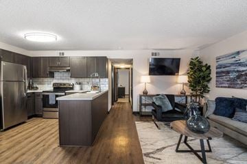 Pensacola apartment for rent - A modern kitchen with a wooden island and a living area with a couch and a plant.