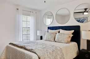 Pensacola apartment for rent - a bedroom with a bed and two mirrors above it at The Lorient Apartments, Florida