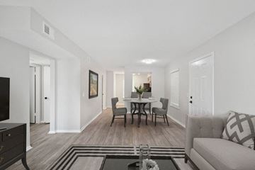 Metairie apartment for rent - A living room with a grey couch, a coffee table, and a dining table set up in the background.