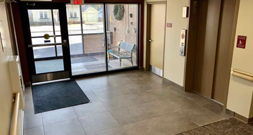 Appleton triplex for rent - A hallway with a black mat on the floor and a bench by the window.